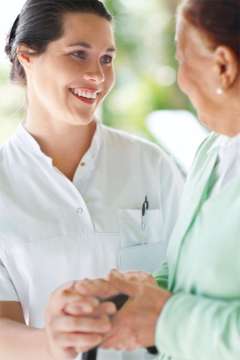 An employee holding the hand of an older patient