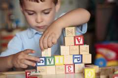 boy playing with wooden letter blocks