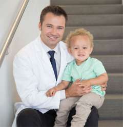 Luke Macyszyn, MD sitting with child on steps