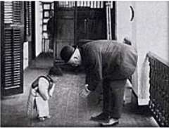 Man wearing a hat and a child bowing to each other