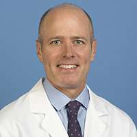 Head shot of S. Thomas Carmichael, MD wearing a white lab coat, smiling at the camera