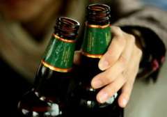 Two beer bottles with a hand reaching toward them.