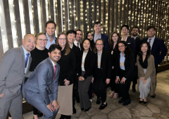 Group photo of professionals posing together in formal attire with twinkling lights in the background.
