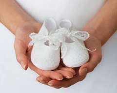 Woman holding white baby shoes in her hand
