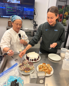 Two people in a kitchen preparing and serving desserts on a counter.