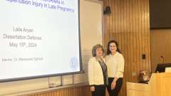 Dr. Aryan stands next to a woman in front of a slide.