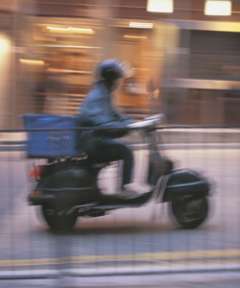 Blurry photo of person driving moped