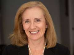 Dr. Carol Mangione wearing a black top and a pearl necklace