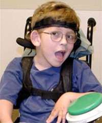 child with cerebral palsy wearing glasses sitting in a wheelchair and smiling