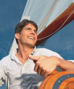 Man smiling and driving sail boat