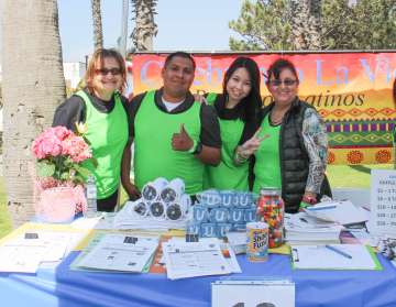 Four individuals in green shirts pose together at a festive event table.