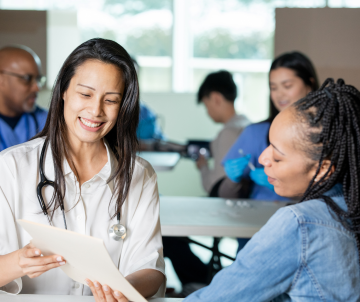 Healthcare professional smiling while discussing documents with a patient at a clinic.