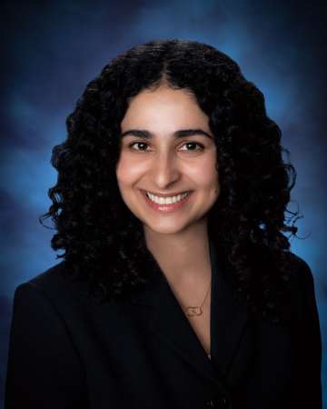 Head shot of Nicki Karimi-Mostowfi in a black suit jacket, smiling at the camera