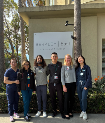 Six people standing before a Berkley East building sign