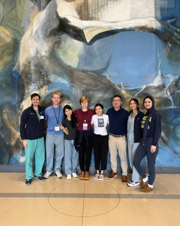 Eight Neurology Chief Resident posing in front of a painted mural.