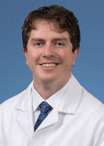 Head shot of Dylan Calame in a white coat, looking at camera