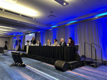 Six presenters sitting on a long table on the podium during the Society of Cardiovascular Anesthesiologists 2024 Annual Meeting.
