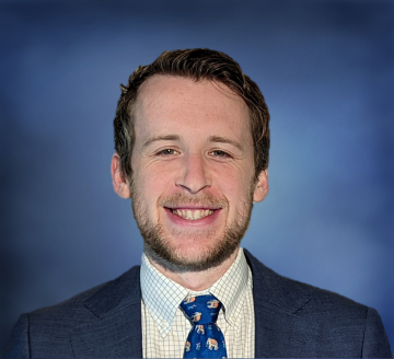 Head shot of Jacob Klickstein in a suit, smiling at the camera