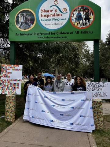 NDD Fellowship staff composite holding banner under park entrance arch