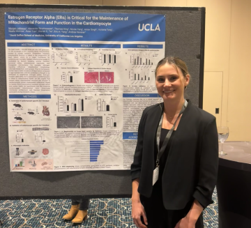 Photo of Morgan Johnson, who has blonde hair and is wearing a black blazer, posing in front of her research poster