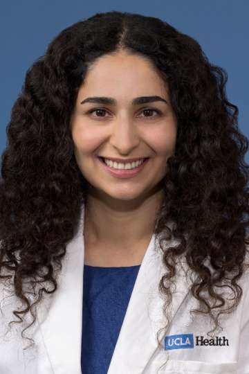 Head shot of Nicki Karimi-Mostowfi, MD in white coat, smiling at the camera