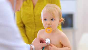 Doctor holds stethoscope to a baby's chest