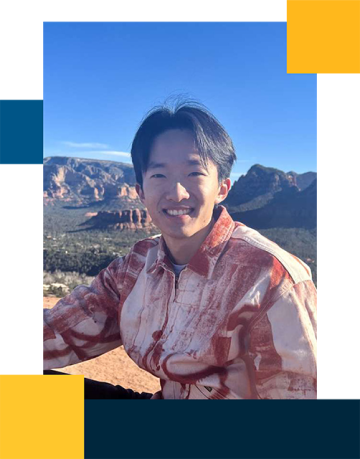 Qicong Sheng wearing a red button down in the outdoors with mountains in the background