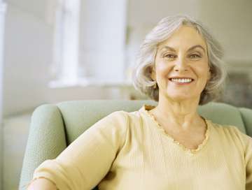Senior woman smiling and sitting on a couch
