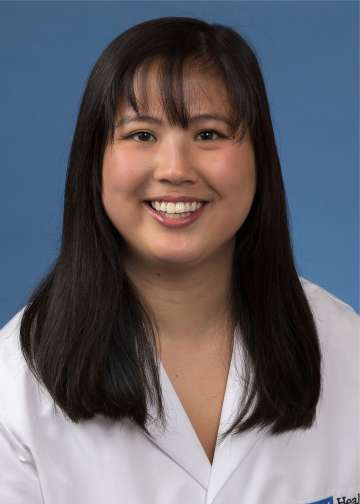 Head shot of Maia Giombetti in white lab coat, smiling at camera