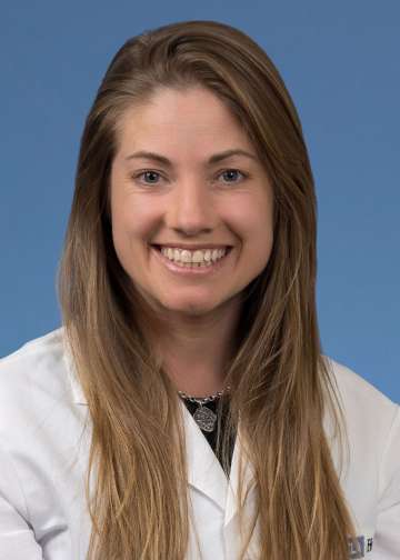 Head shot of Neva Lundy in a white coat, smiling at camera