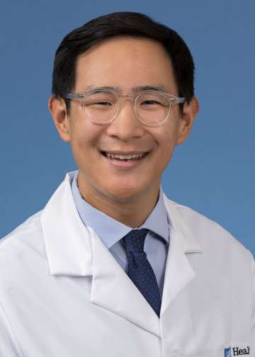 Head shot of Jerry Shen in a white coat, smiling at camera