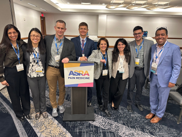 Conference attendees standing around an ASRA Pain Medicine podium