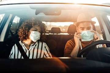 Couple in a car wearing masks, enjoying each other's company.