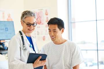 Doctor holding a tablet showing something to a patient