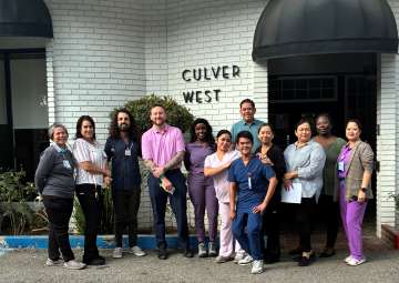 Group of people, some in scrubs, standing outside a building labeled 'Culver West'.