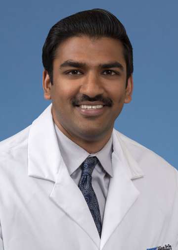 Head shot of Rohan Rao in a white coat, smiling at camera
