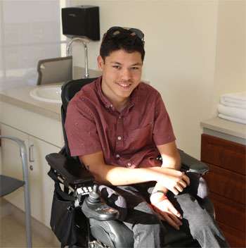 Young man with cerebral palsy sitting in a wheelchair and smiling
