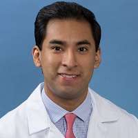 Head shot of Erick Juarez in white lab coat, smiling at camera