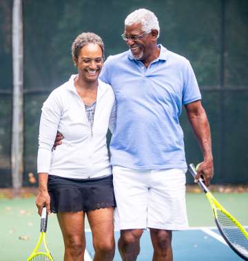A senior couple together on the tennis court.