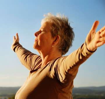 Mature female enjoying freedom against sky with arms outstretched