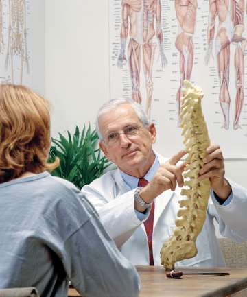 Doctor showing patient spine replica