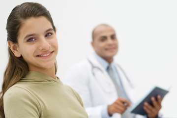 Girl smiling sitting next to doctor