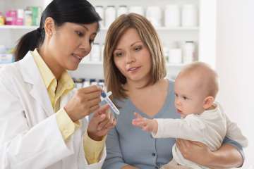 Doctor instructing mother how to use medicine syringe