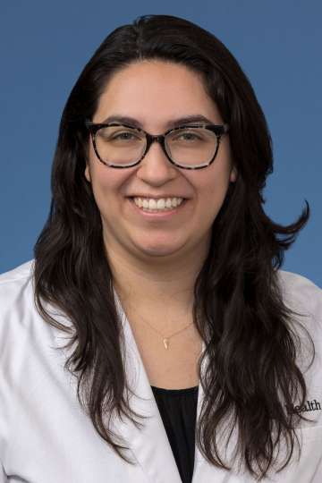 Head shot of Brenda Gutierrez, MD, PhD in a white coat, smiling at the camera