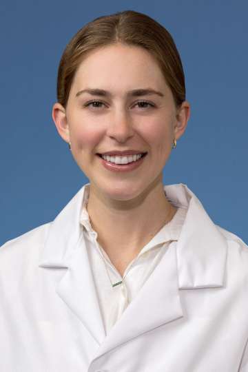 Head shot of Clare Schrodt, MD in white lab coat, smiling at camera