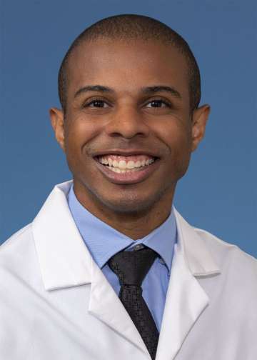 Head shot of Paul Lewis, MD, MS in white coat, smiling at camera