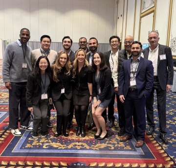 Conference attendees posing together in a hotel ballroom, wearing name badges.