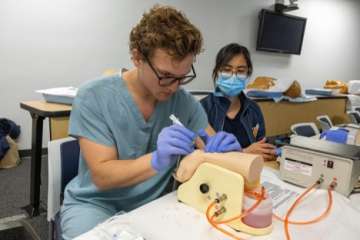 a hospitalist in a training practicing needle injection with a prosthetic