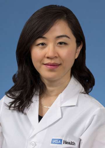 Head shot of Irma Zhang in a white coat, smiling at camera.