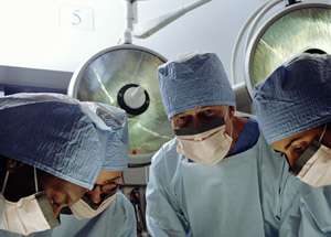 Three surgeons wearing masks at an operating table